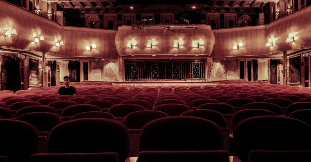 A man, alone, in an auditorium